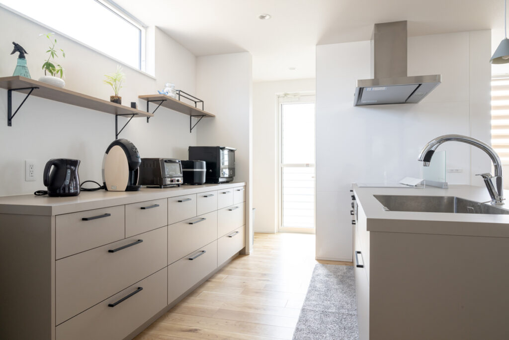 明るい窓際にあるカフェのようなオープン収納棚と機能的なキッチン