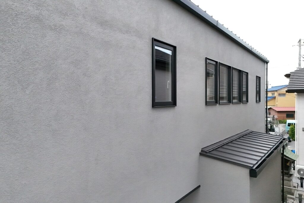 表情豊かなグレーの塗り壁外壁と黒いサッシのディテール