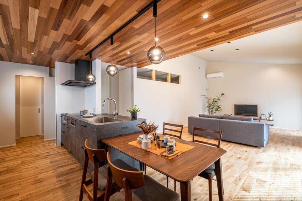 開放的な吹き抜けと木目調の天井が特徴的な、洗練されたモダンなリビング・キッチン。