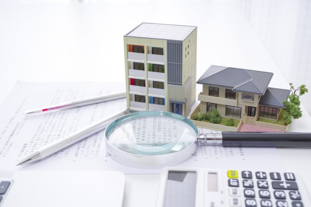 賃貸マンションと一戸建て持ち家の模型を並べて比較。将来の住まい選びをシミュレーションするイメージ。