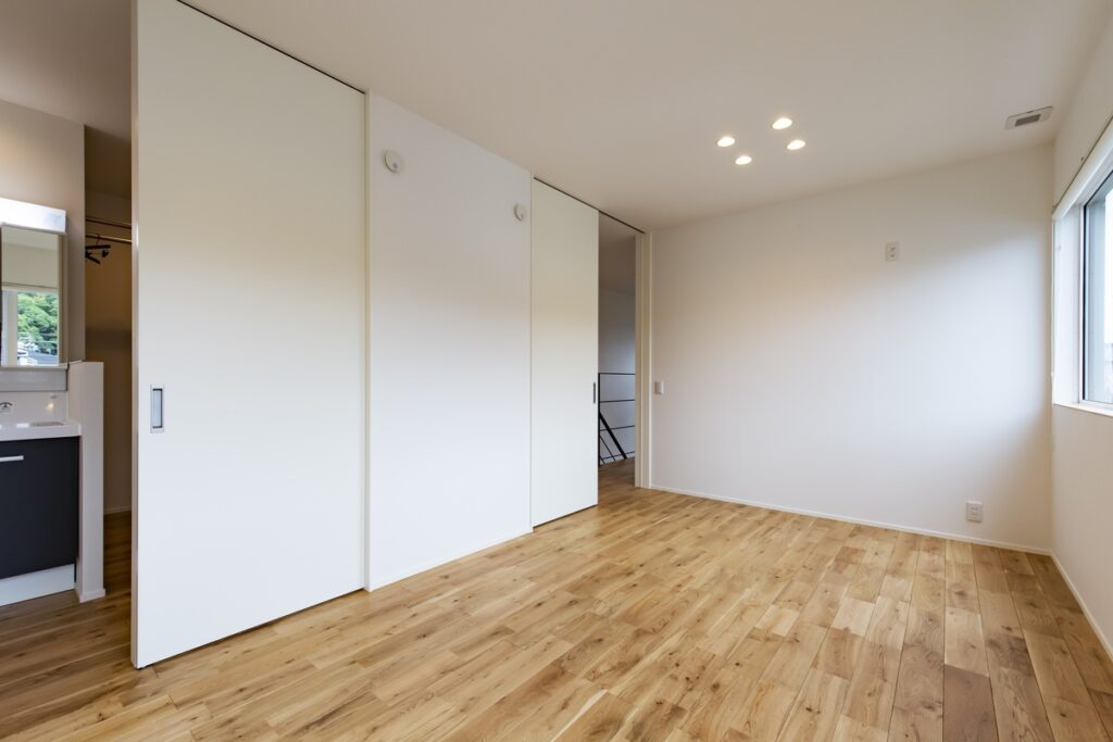 白い引き戸で空間を仕切ることができる、明るい無垢フローリングの多目的ルーム。
