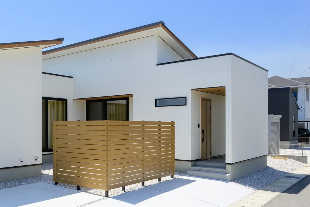 白い外壁と木目調のフェンスが調和したモダンな平屋の外観