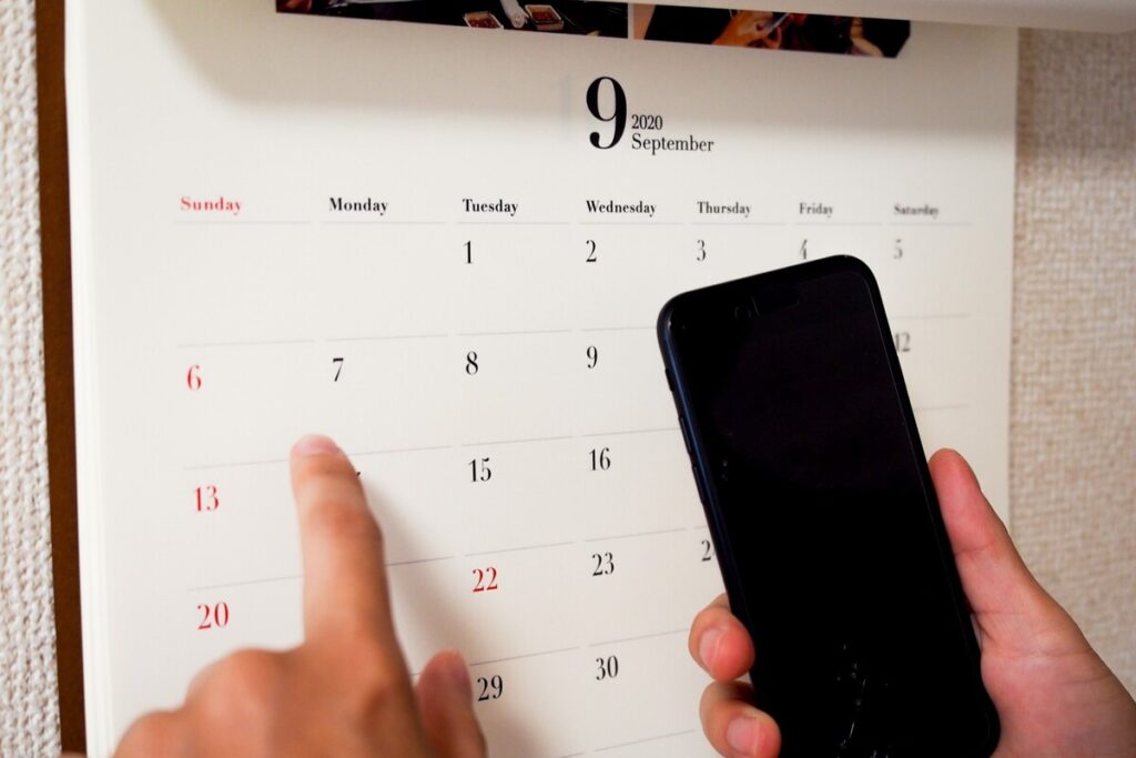 カレンダーを指差し、スマホで予定を確認する様子。