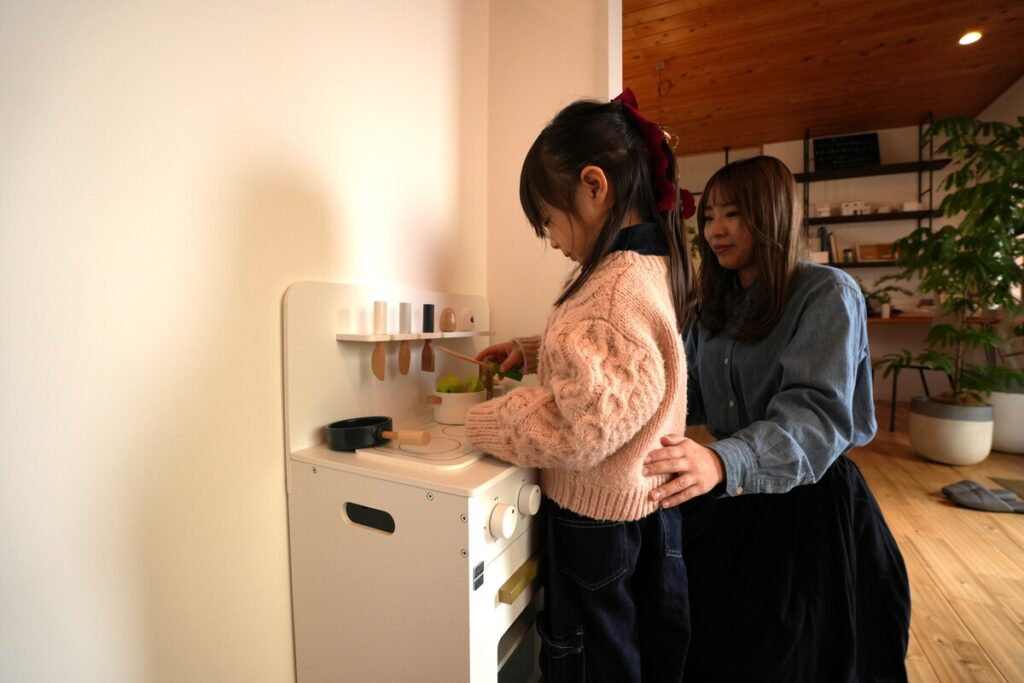 木の温もりを感じる空間でおままごとをするお子様と、優しく見守るスタッフ。契約前の相談に集中できるよう配慮されたサポート体制のイメージ。