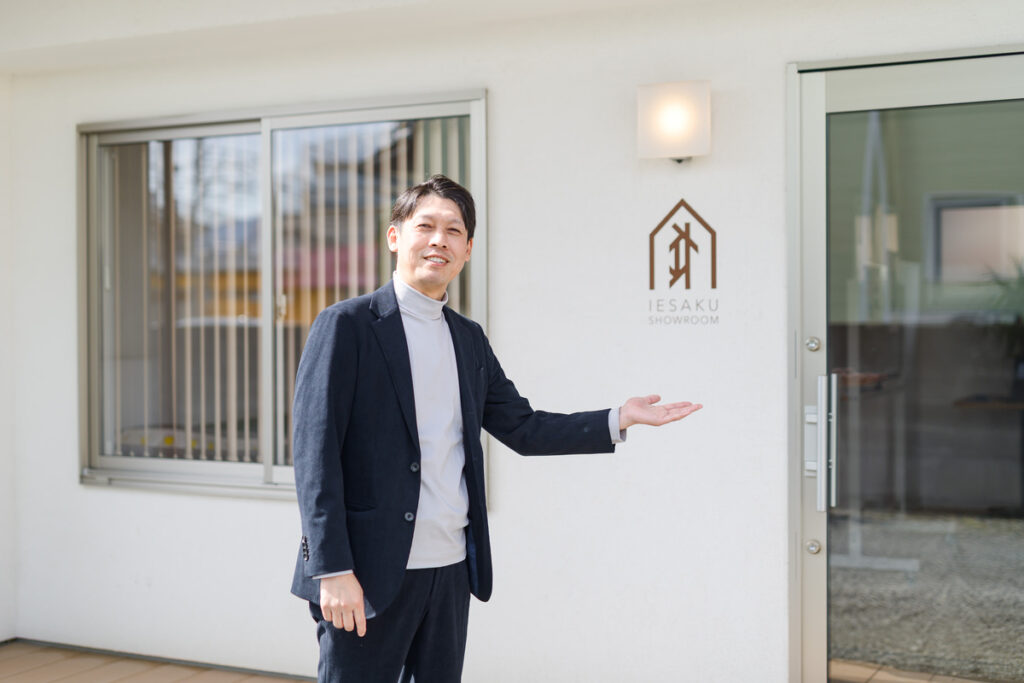 IESAKU SHOWROOM(家咲ショールーム)の前で、笑顔で案内をするスタッフ。