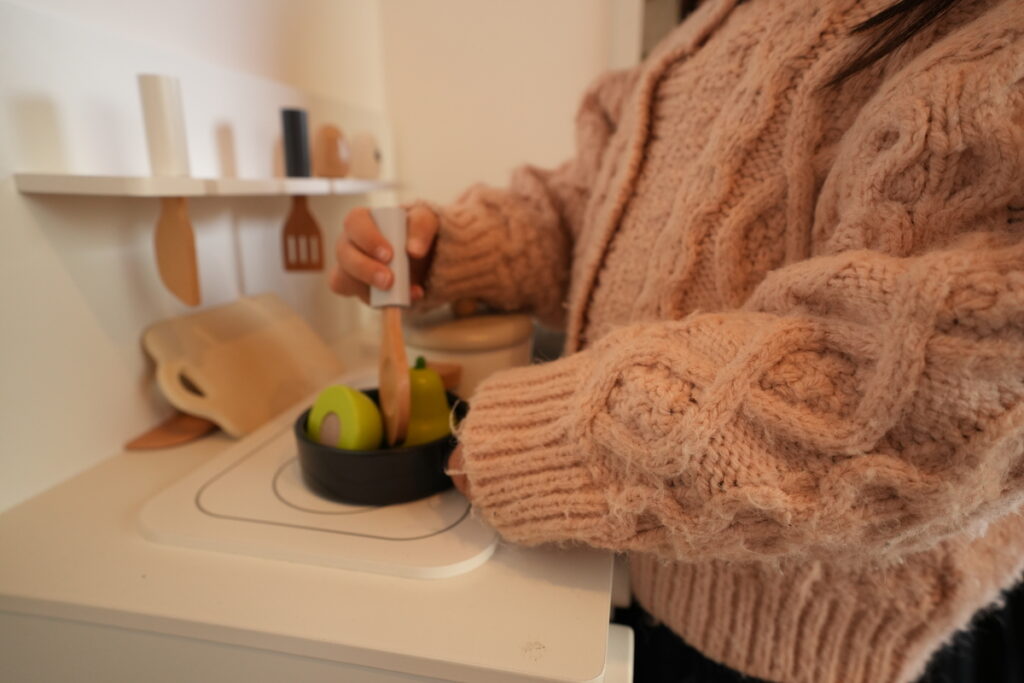 木のおもちゃのキッチンで遊ぶお子様の様子と、家族の温かみが伝わる家づくり