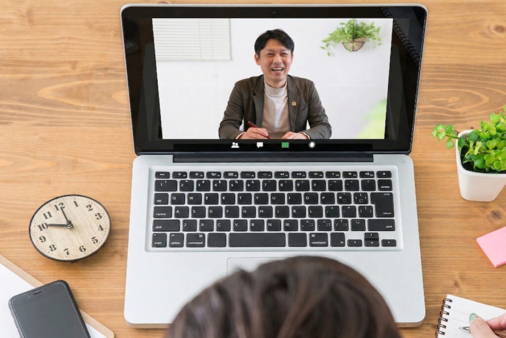 ノートパソコンの画面越しに、笑顔のスタッフと直接会話をしながら自宅でリラックスして参加できるオンライン相談会の実施風景。