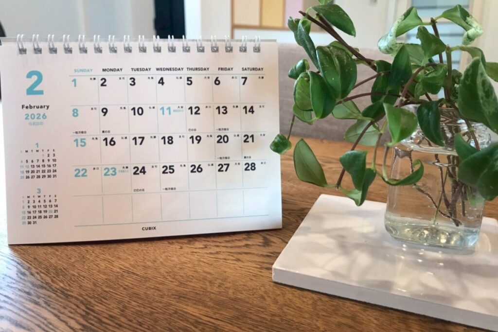 2026年2月のカレンダーと観葉植物が置かれた、日当たりの良い打合せテーブル。