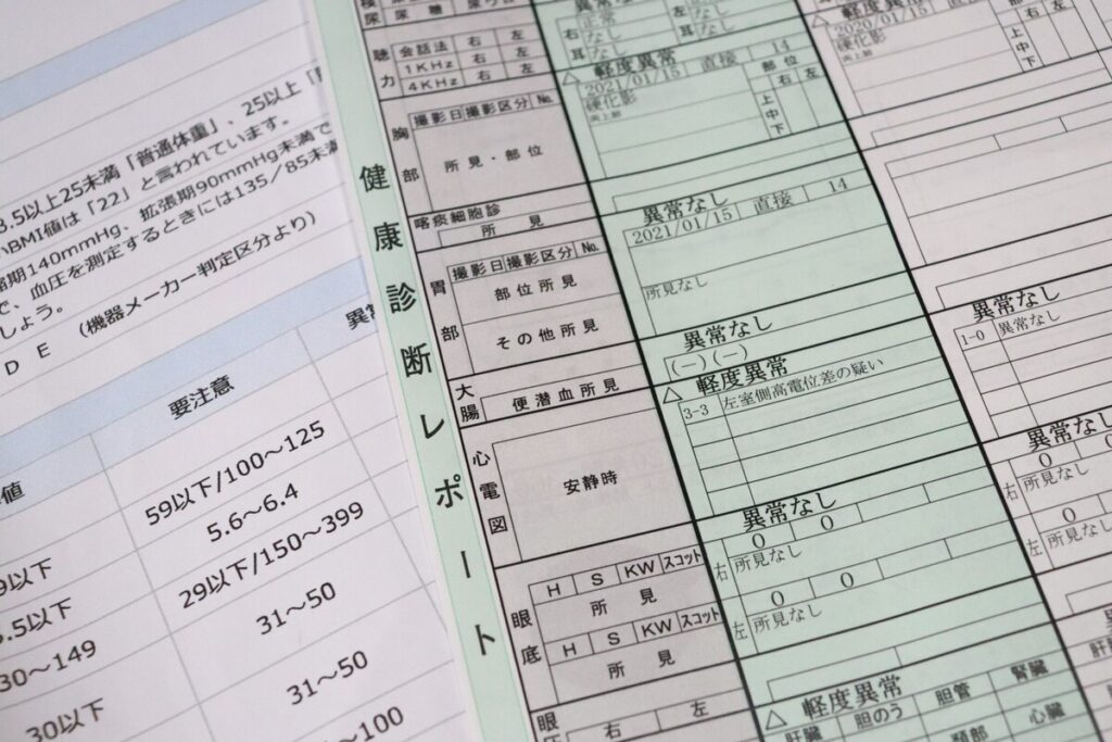 「健康診断レポート」の判定結果。再検査や経過観察の項目が記載された書類の接写。